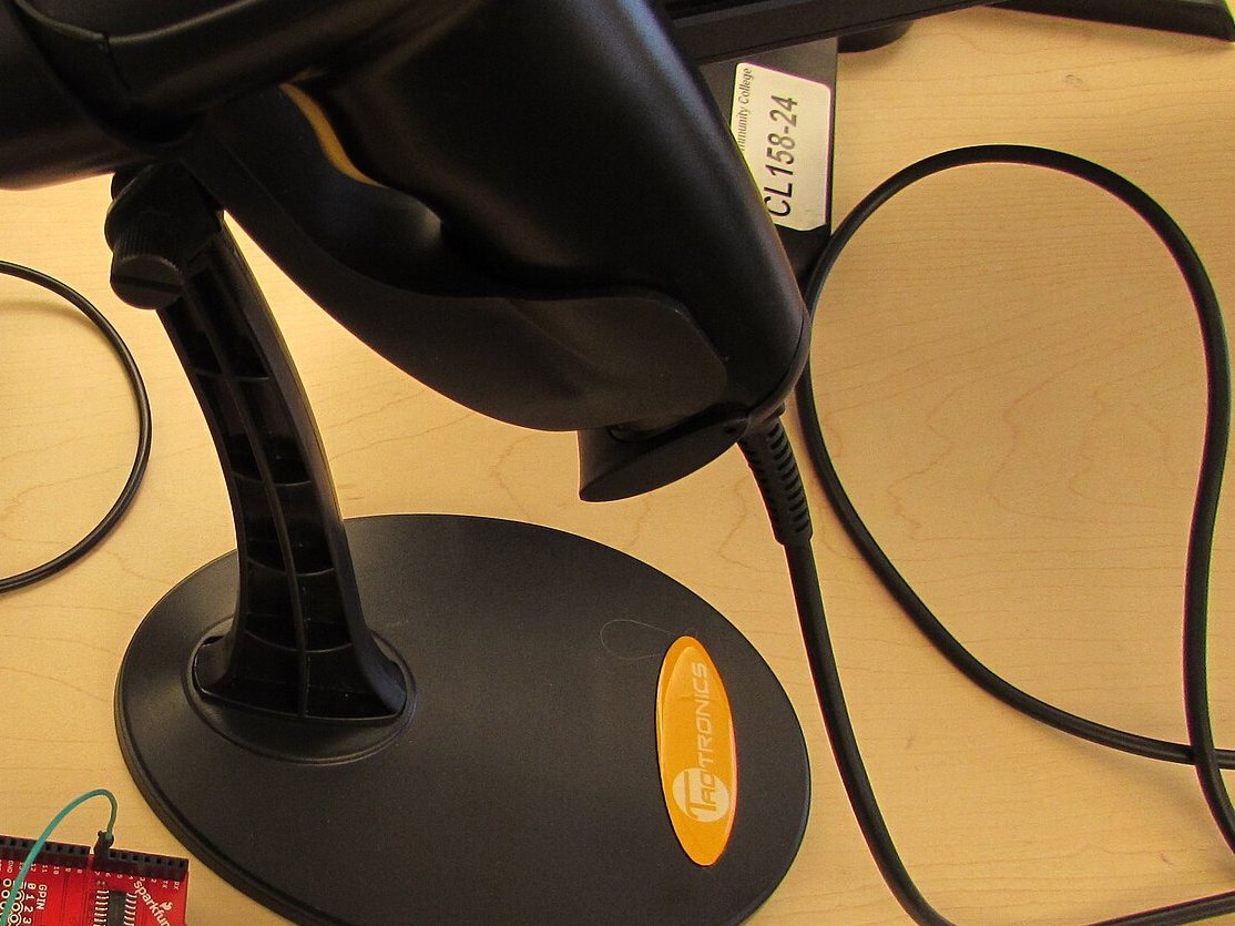 A handheld barcode scanner on a bench