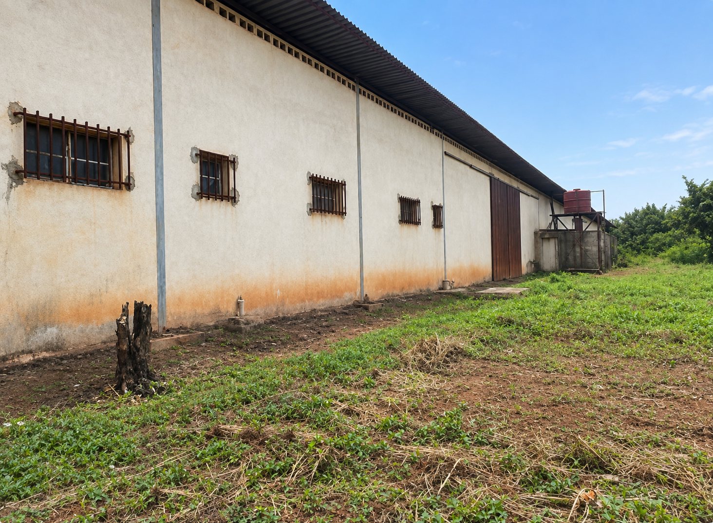 Long side wall of the warehouse with barred windows and a raised water tank